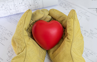 Maintenance worker hands in work gloves holding a heart